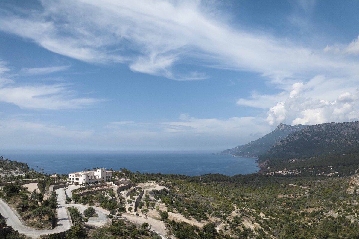 A large white building sits on top of a hill overlooking the ocean