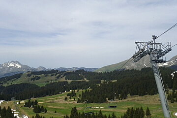 A ski lift going up a hill with mountains in the background