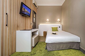 A hotel room with a single bed and a flat screen tv