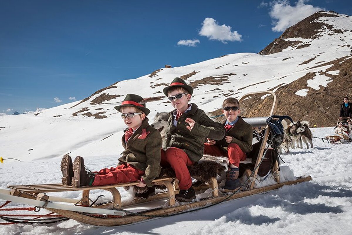 A group of children are riding on a sled pulled by huskies