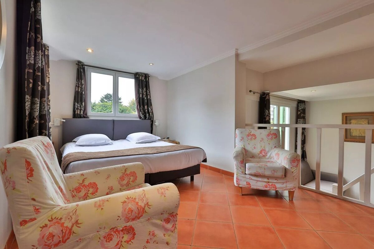 A bedroom with a bed and two chairs with flowers on them