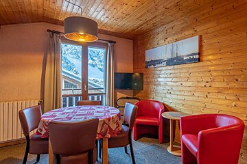 A living room with a table and chairs and a painting on the wall