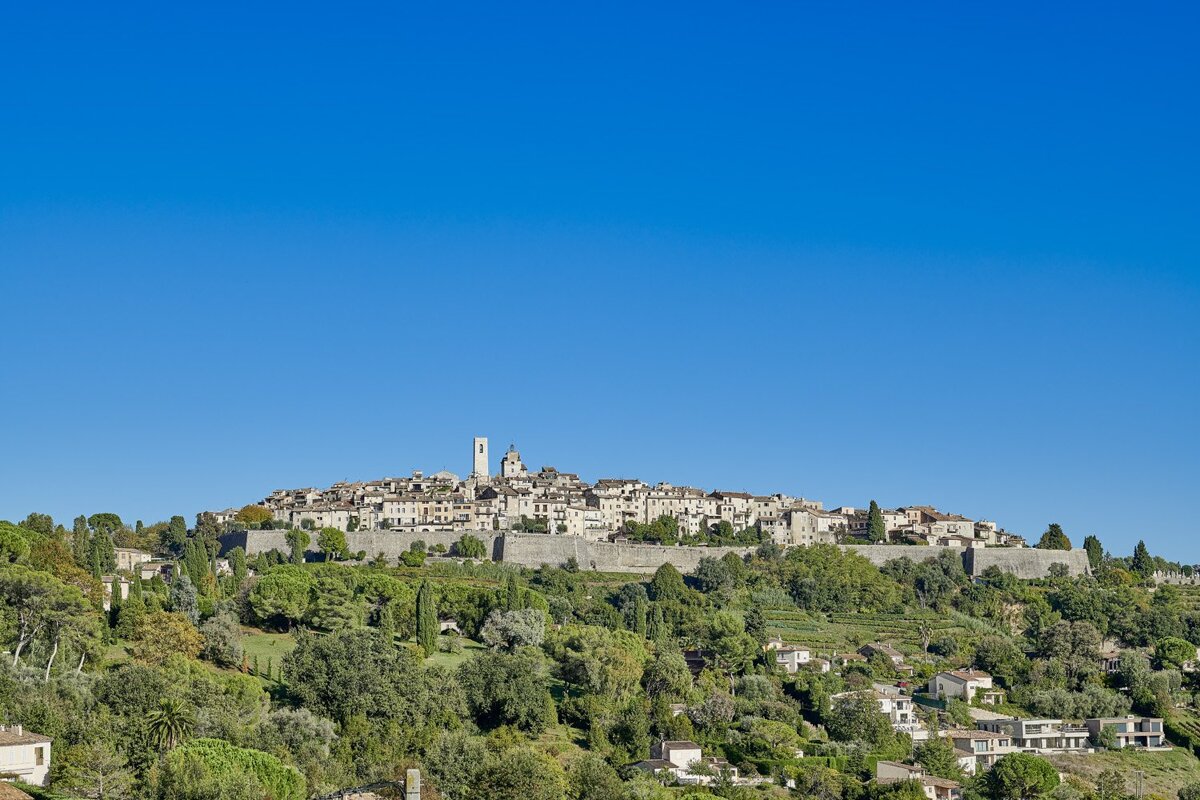 A small town sits on top of a hill surrounded by trees