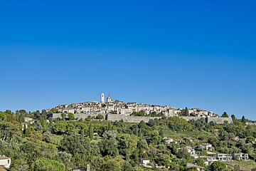 A small town sits on top of a hill surrounded by trees