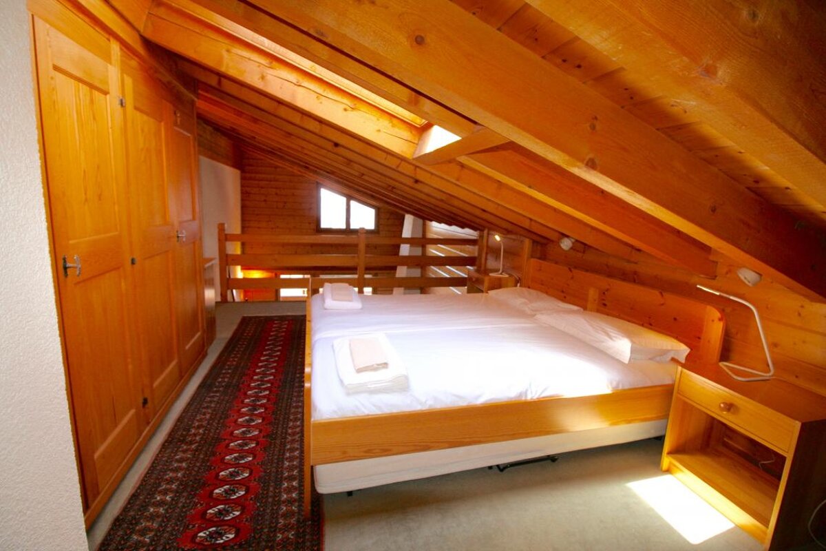 A bedroom with a wooden ceiling and two beds