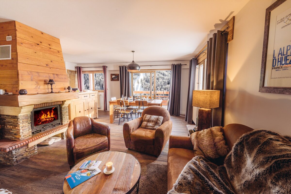 A living room with a fireplace and a poster that says alp d' huez