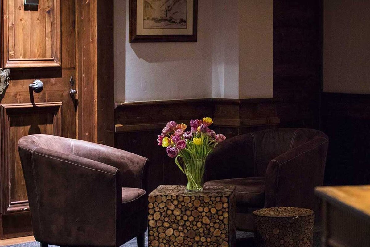 A vase of flowers sits on a wooden table between two chairs
