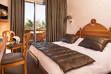 A hotel room with a single bed and a helmet on the chair