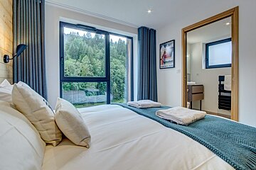 A bedroom with a large window and a picture on the wall that says