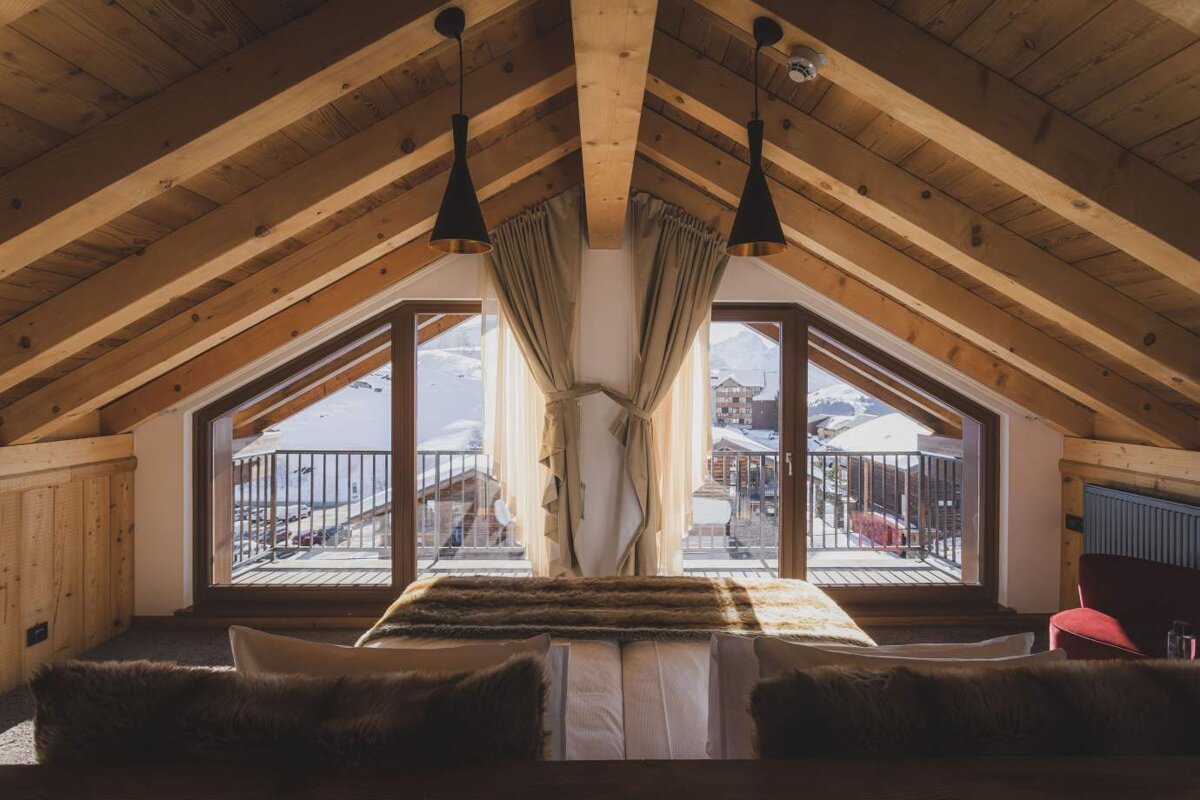 A bedroom with a bed and a balcony with a view of the mountains