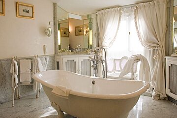 White free standing bath in the middle of a white marbled bathroom