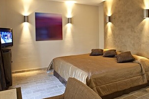 Large double bedroom with gold covered bed and modern silver light fittings