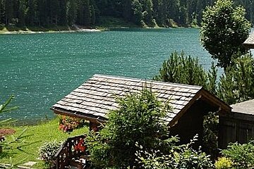 image of a large lake with the roof top of a building and the building in the foreground, green grass on the edge of the lake