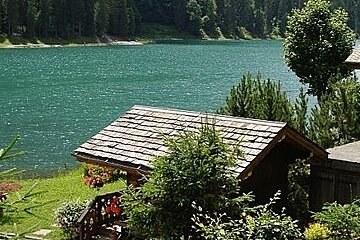 image of a large lake with the roof top of a building and the building in the foreground, green grass on the edge of the lake