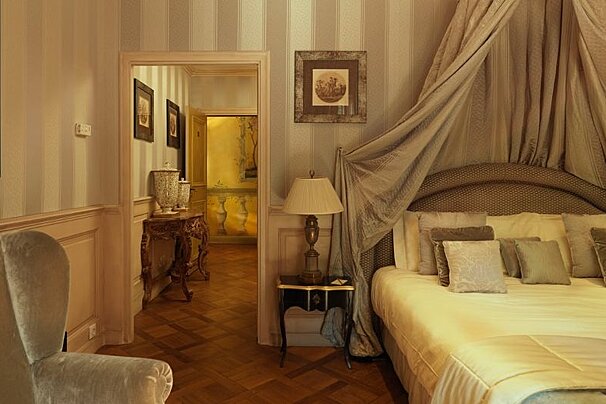 Double bedroom with arm chair and entrance to a separate suite