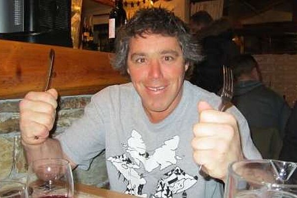 An image of a man holding a knife and fork, ready to eat a meal at a restaurant in a french ski resort