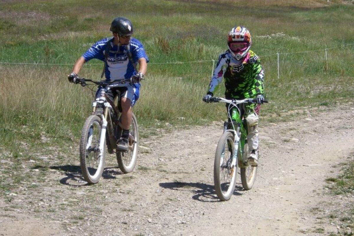 a picture of a mountain bike coach teaching a child on a bike