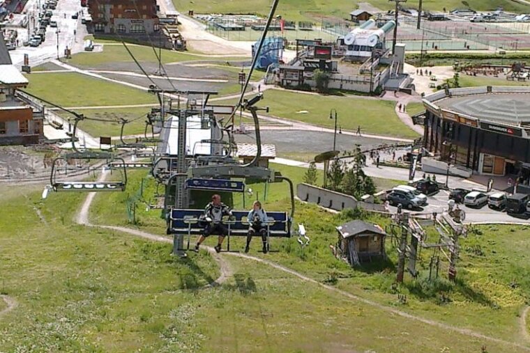 a picture of a couple on a chair lift with their mountain bikes