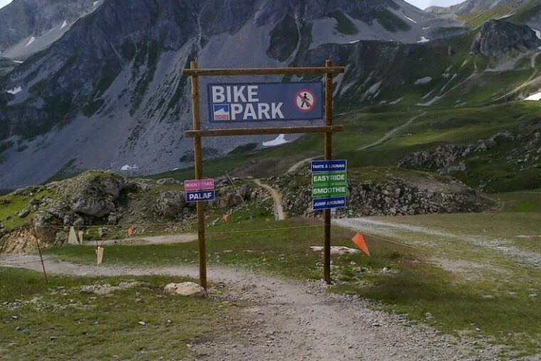a picture of a gate with sign posts marking the start of a bike park