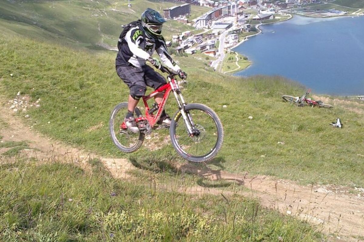 A person riding a bike on a grassy hill with a lake in the background