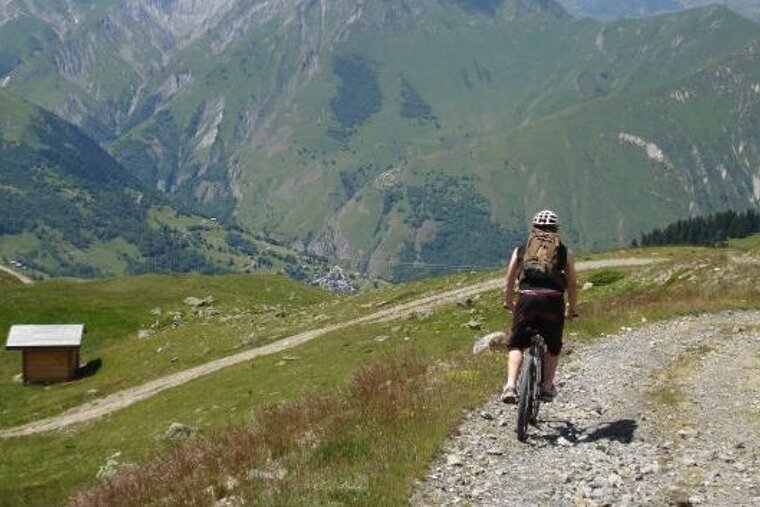 a picture of a man mountain biking on a fire road in meribel