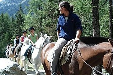 image of a woman on a horse with a class of people on horses behind here on a trail in a forest