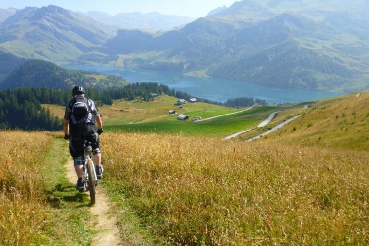 a picture of a mountain biker heading down a trail towards a lake