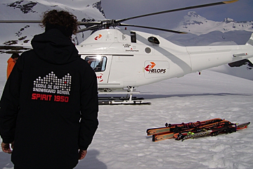 a picture of a mountain guide in a branded jacket near a helicopter