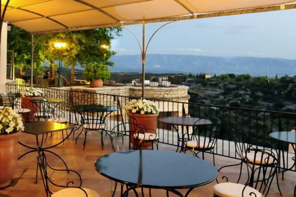 Covered raised terrace with black tables and white chairs at nights with views over the countryside