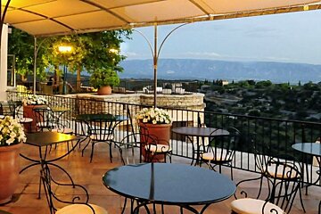 Covered raised terrace with black tables and white chairs at nights with views over the countryside