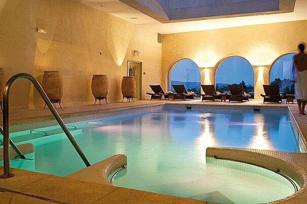 Indoor lit pool at night with floor to ceiling circular windows at the other end