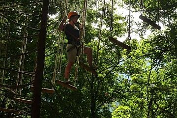 A woman is standing on a ropes course in the woods