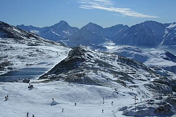 Skiers on a snowy slope with mountains in the background
