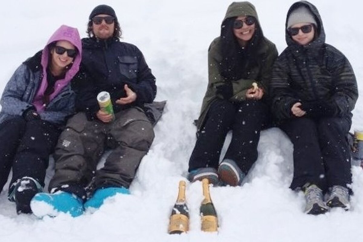 an image of people sitting in the snow with bottles of champagne