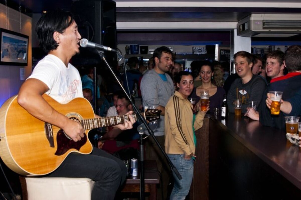 A man singing into a microphone while playing a guitar