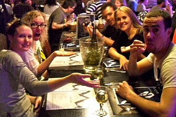 A group of people sitting at a table with a menu that has the letter m on it
