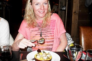 A woman in a pink shirt is sitting at a table with a plate of food