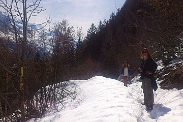An image of 2 hikers in a snowy forest in Chamonix Mont Blanc with Mont Blanc glacier in background