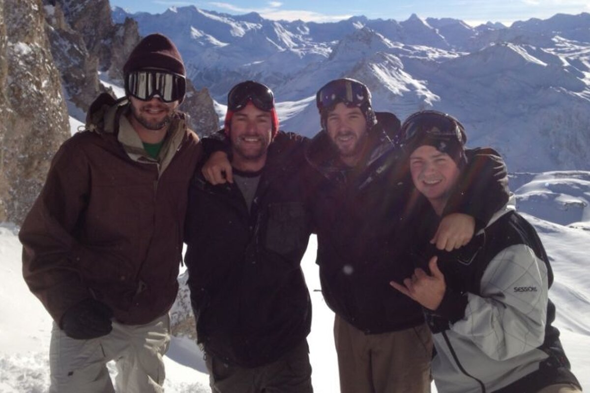 Four men posing for a picture with one wearing a jacket that says salomon