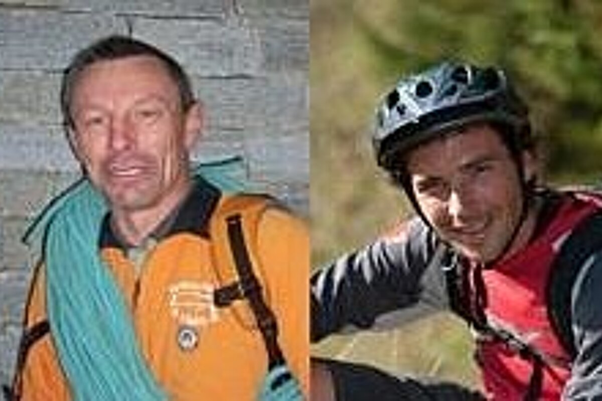 Two men are posing for a picture and one of them is wearing a helmet