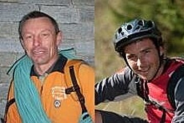 Two men are posing for a picture and one of them is wearing a helmet