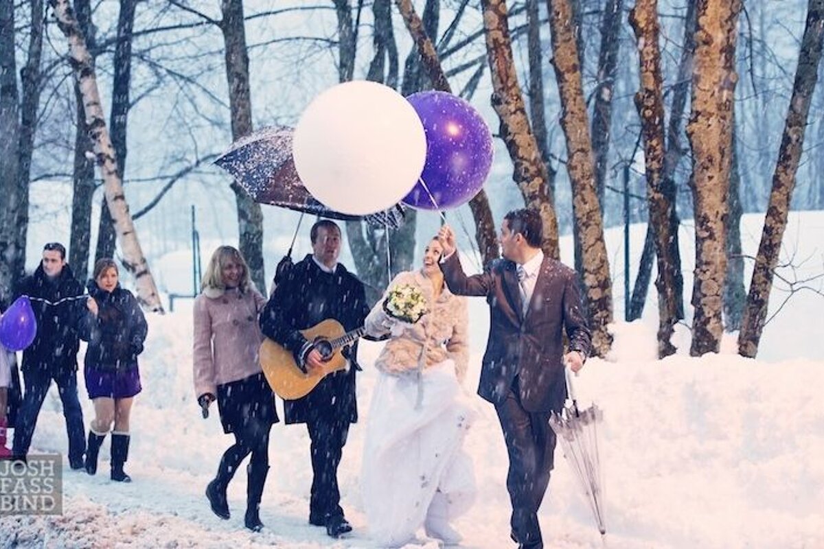 a picture of a wedding party with balloons walking in the snow