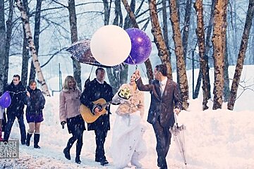 a picture of a wedding party with balloons walking in the snow