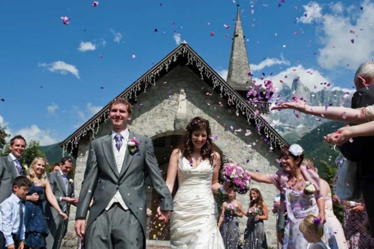 a picture of a bride and groom leaving a church with confetti in the air