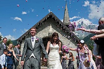 a picture of a bride and groom leaving a church with confetti in the air