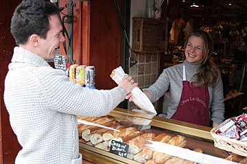 a woman handing a man a sandwich over the counter