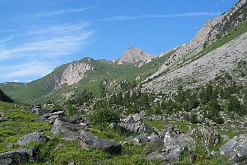 image of some rocks and grass on the mountains with the blue sky and wispy clouds above