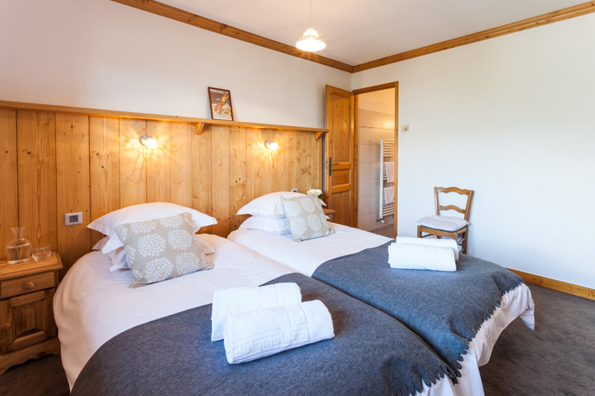 A bedroom with two twin beds and a chair