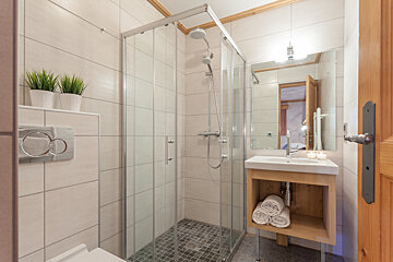 A bathroom with a walk in shower and a sink