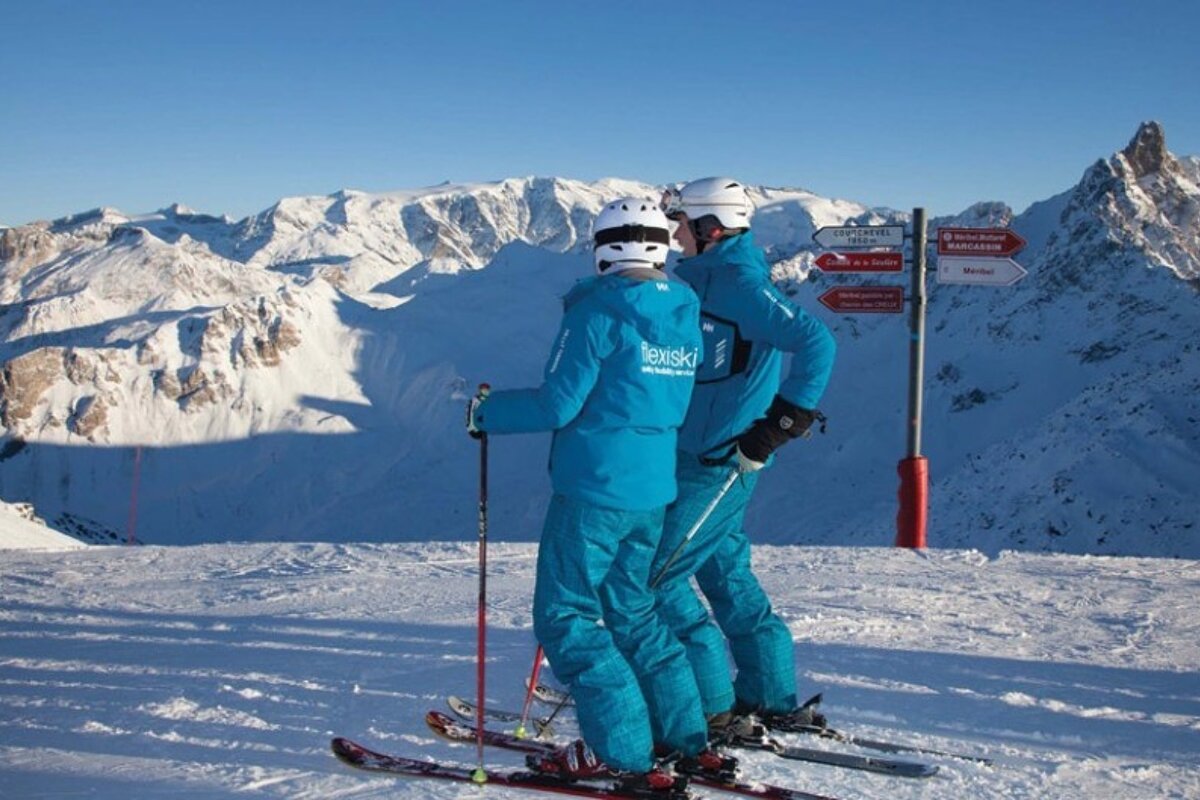 Two skiers in blue ski gear on flat run of a mountain